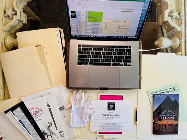 desktop view of archive materials, a laptop, and archival gloves